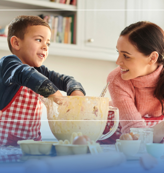 Immagine di donna e bambino in cucina mescolano ingredienti in una ciotola su un tavolo con elementi grafici arrotondati.